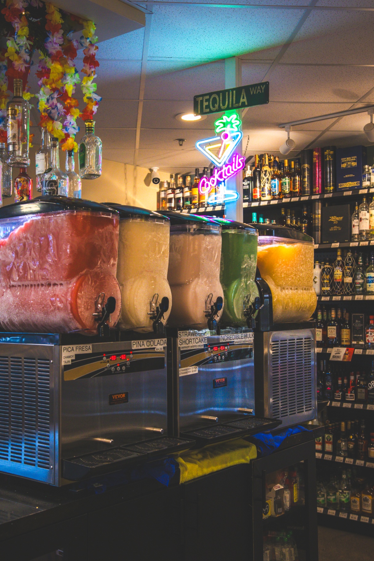 Quick Corner Liquor frozen cocktail machines under the Tequila Way and Cocktails neon signs