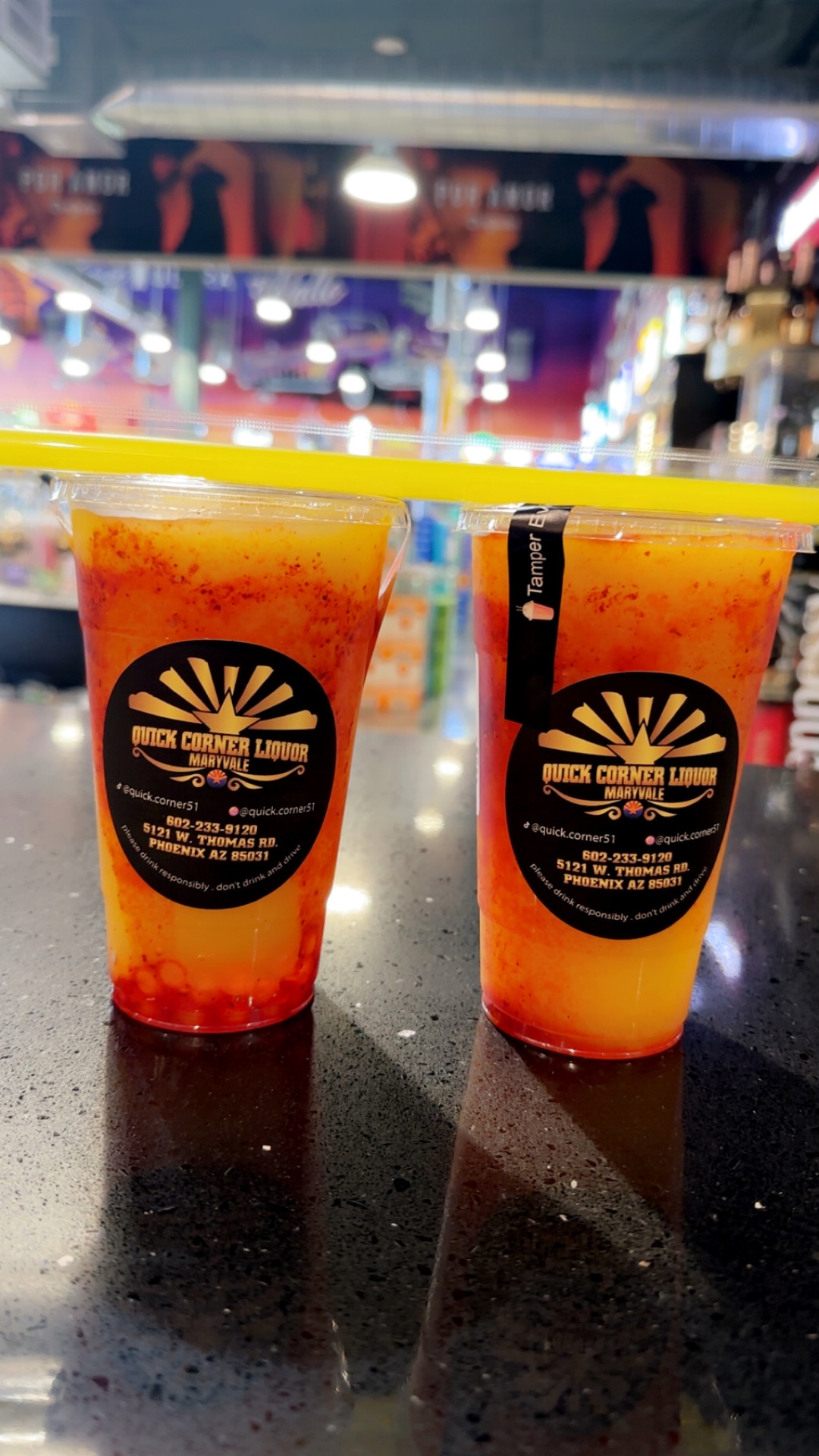 Two chamoy mangonada alcohol slushies in Quick Corner Liquor branded cups on the Maryvale counter