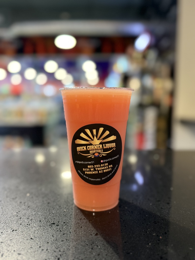 Coral-orange frozen paloma slushie on the Quick Corner Liquor counter