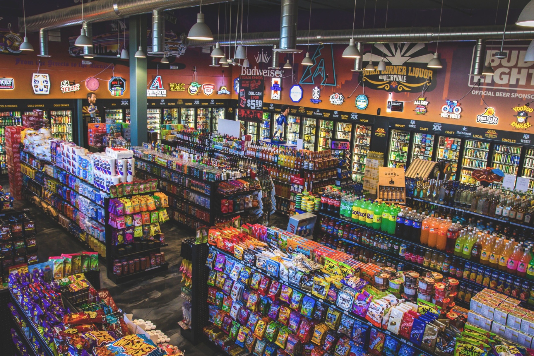 Quick Corner Liquor interior — wall of coolers, neon signs, and packed aisles in Maryvale Phoenix